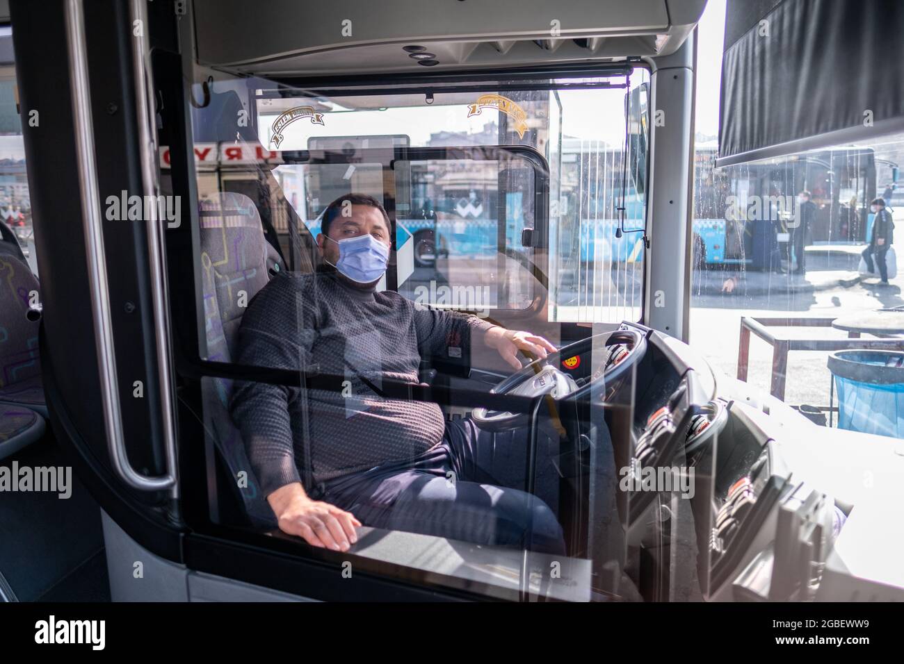 Eminonu, Istanbul, Turchia - 02.27.2021: Istanbul conducente di autobus con maschera sulla sua sedia dietro la zona specchio prima di iniziare il veicolo in quarantena giorni Foto Stock