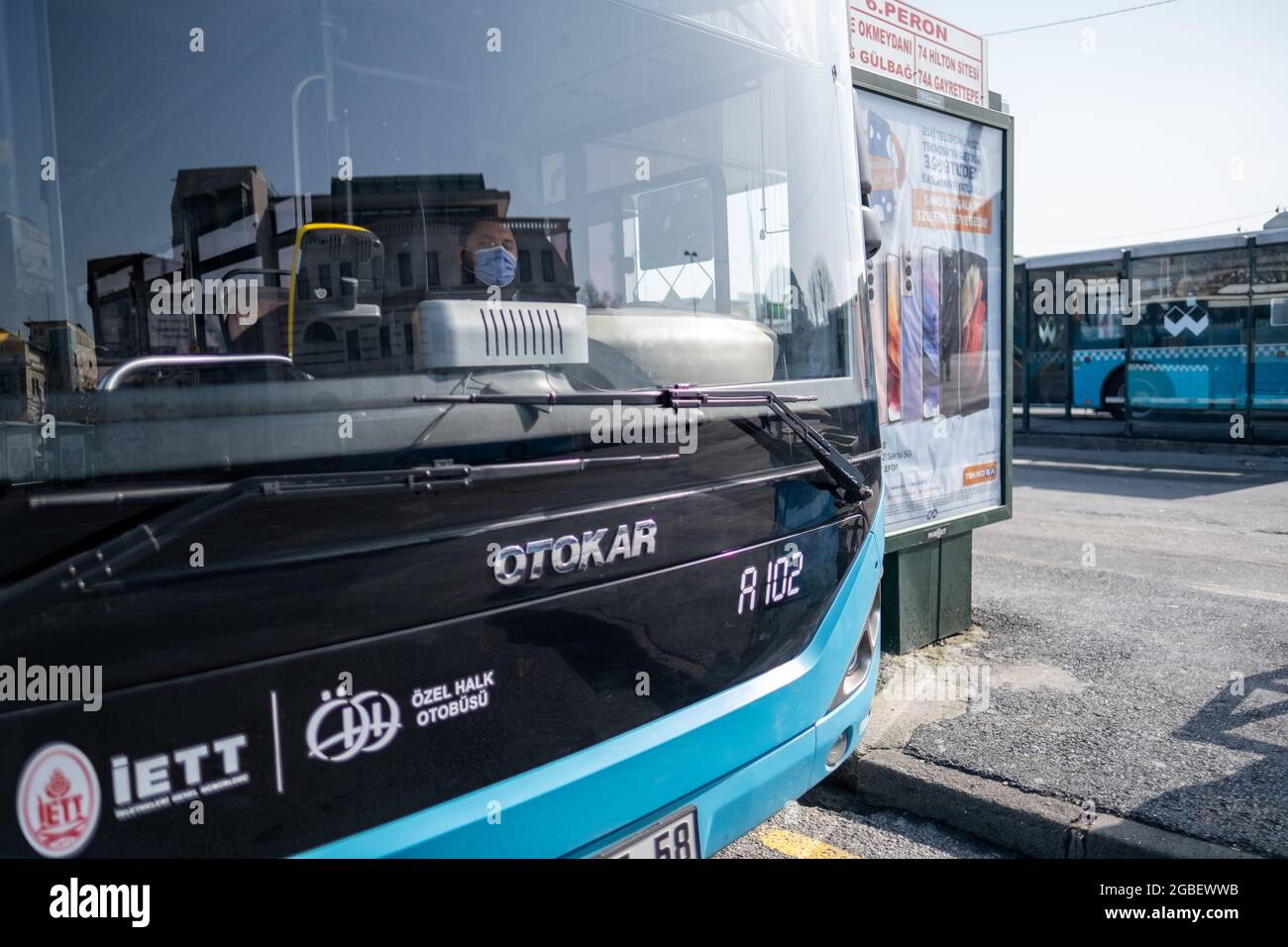 Eminonu, Istanbul, Turchia - 02.27.2021: Conducente di autobus con maschera pone mentre si siede sulla sua sedia di autobus dietro specchio di autobus in giorni di quarantena Foto Stock