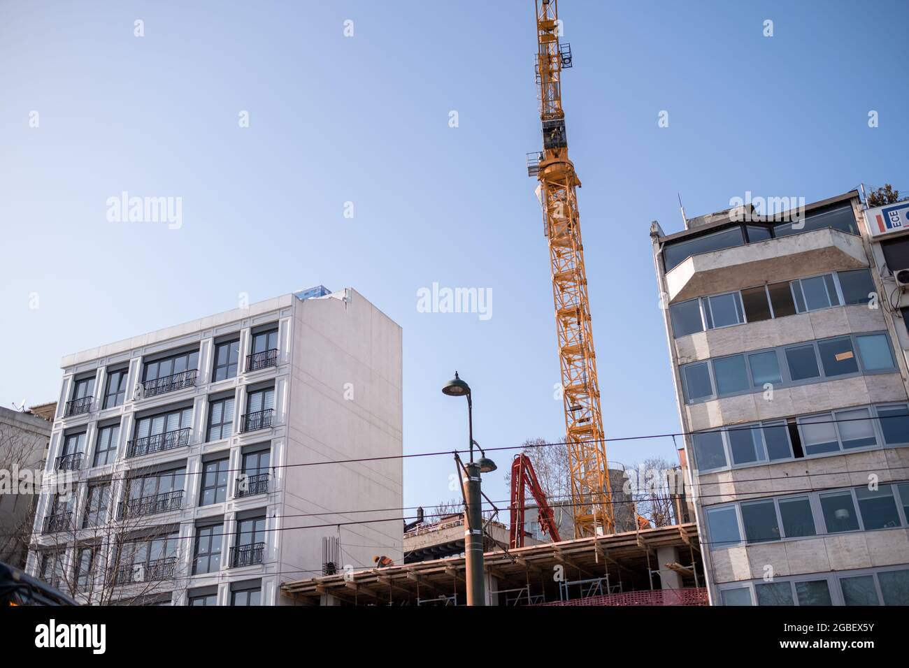 Kabatas, Istanbul, Turchia - 02.26.2021: Gru a torre gialla ad angolo basso per la costruzione in prossimità di alcuni edifici in una giornata senza nuvole Foto Stock