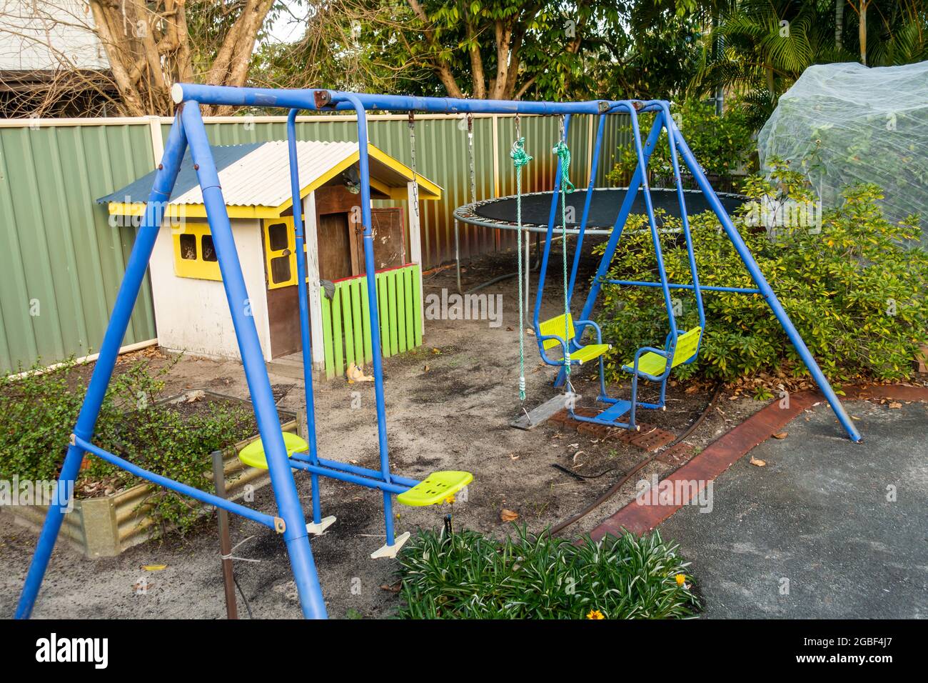 Altalene per bambini, cubby House e Tranpoline in un angolo di giardino posteriore di casa suburbana, Australia. Foto Stock