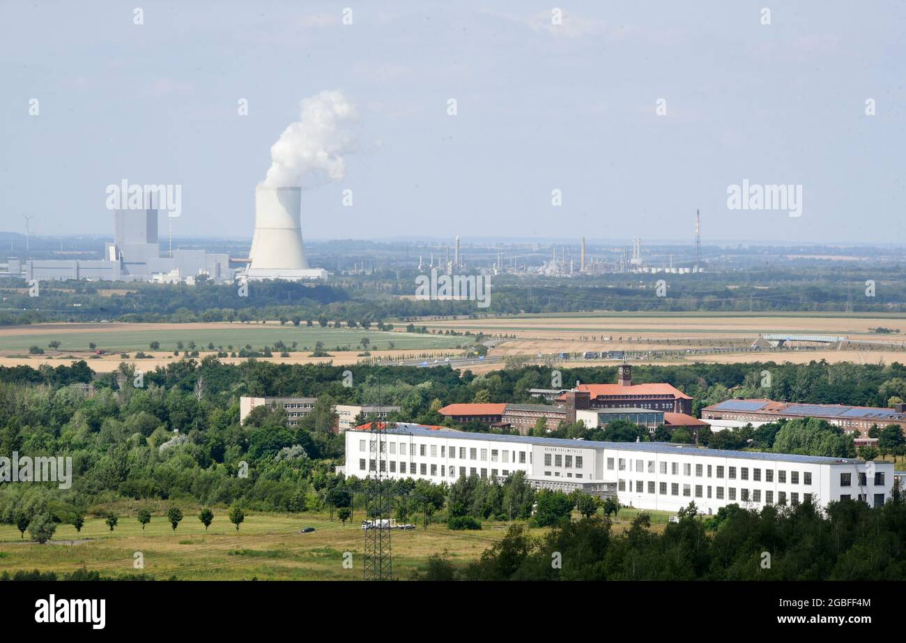 30 luglio 2021, Sassonia, Rötha/OT Mölbis: Da una torre di osservazione alta 30 metri sul sentiero circolare del vecchio cumulo di bottini, i visitatori hanno una vista sul paesaggio, precedentemente sporco e ora verde, dell'industria di recente insediamento e della centrale di Lippendorf (sullo sfondo). La ristrutturazione del percorso circolare con mobili da salotto, cartelli e oggetti di design è uno dei progetti della società di sviluppo del villaggio, che, oltre alla riprogettazione del parco del castello nel centro del paese, comprende anche il cumulo di bottoni, che è stato utilizzato come luogo di pellegrinaggio da attivisti per i diritti civili i Foto Stock