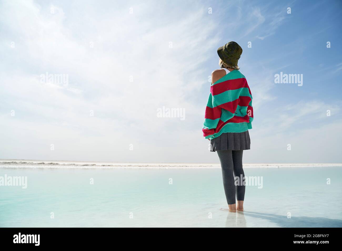 vista posteriore di una donna asiatica turistica in piedi nel mezzo di un lago di sale poco profondo che guarda alla vista Foto Stock