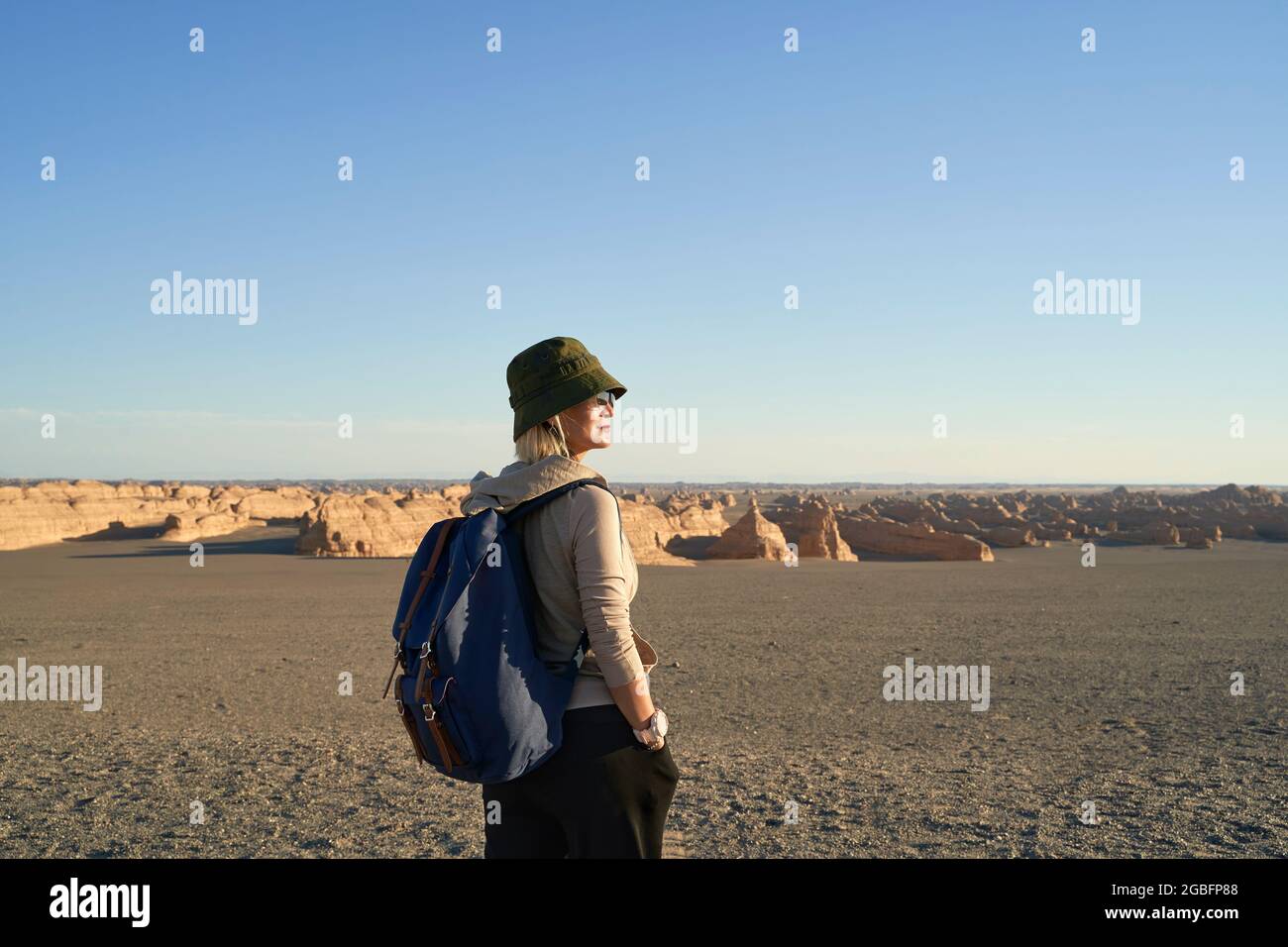donna asiatica zaino in spalla guardando la vista della terra yardang nel deserto di gobi Foto Stock