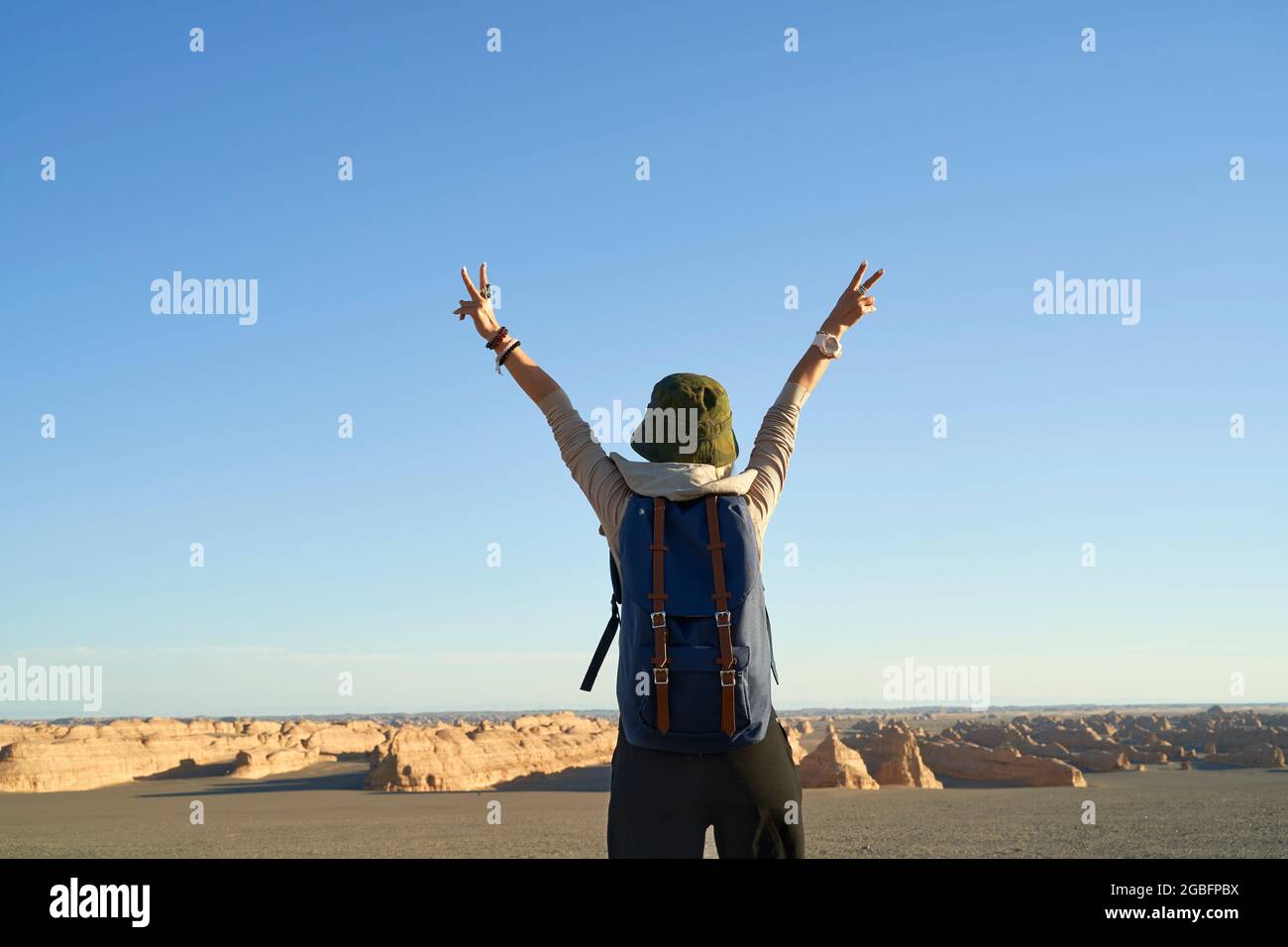 vista posteriore della donna asiatica zaino in spalla guardando la vista della terra yardang nel deserto di gobi, braccio esteso Foto Stock