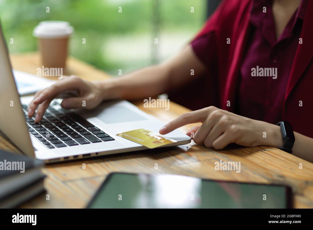 Femmina che immette il numero della carta di credito e il codice di sicurezza via laptop per il pagamento online, online banking Foto Stock