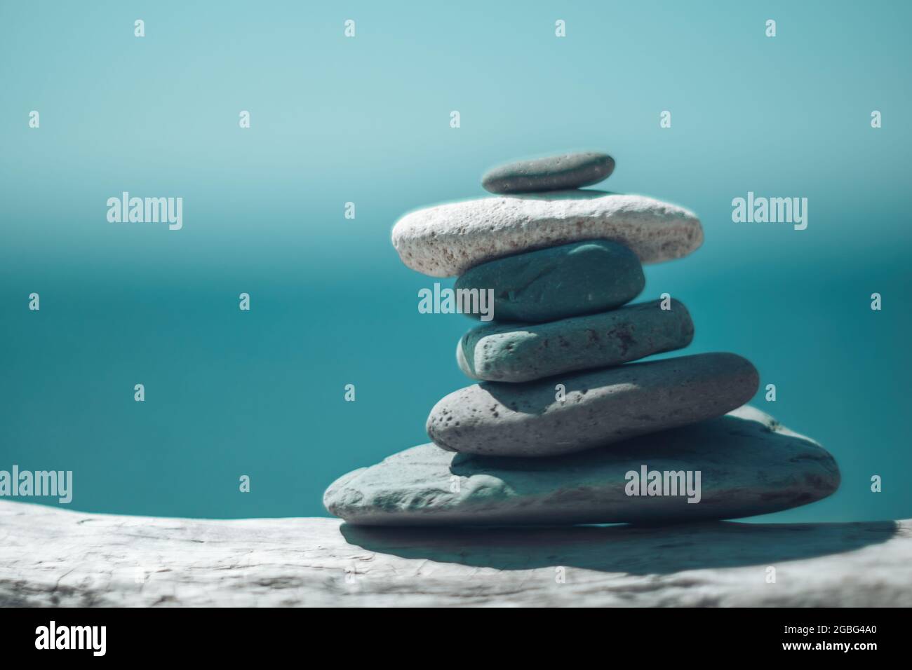 Equilibrata piramide di ciottoli sulla spiaggia in una giornata di sole. Abstract Sea bokeh sullo sfondo. Messa a fuoco selettiva. Pietre Zen sulla spiaggia di mare, meditazione Foto Stock