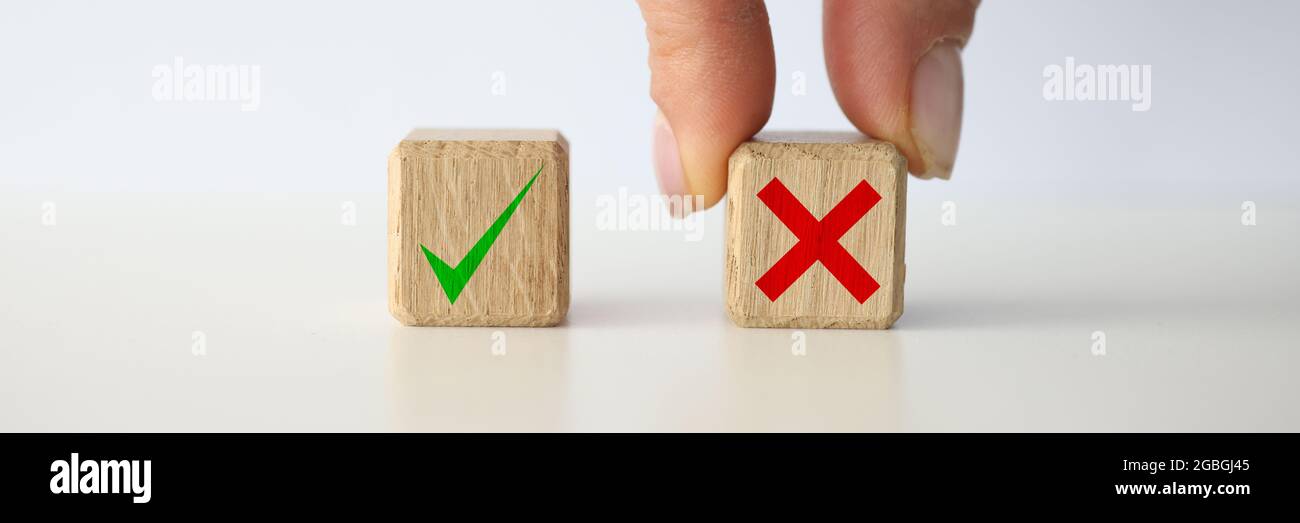 Donna che tiene con sé un cubo giocattolo di legno con una croce scritta primo piano delle mani Foto Stock