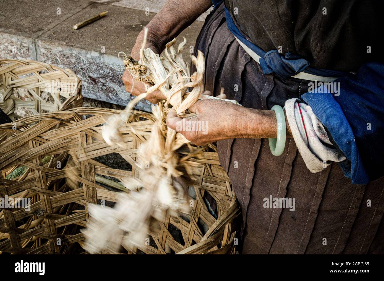 Primo piano delle mani delle donne che tessono la buccia di mais Foto Stock
