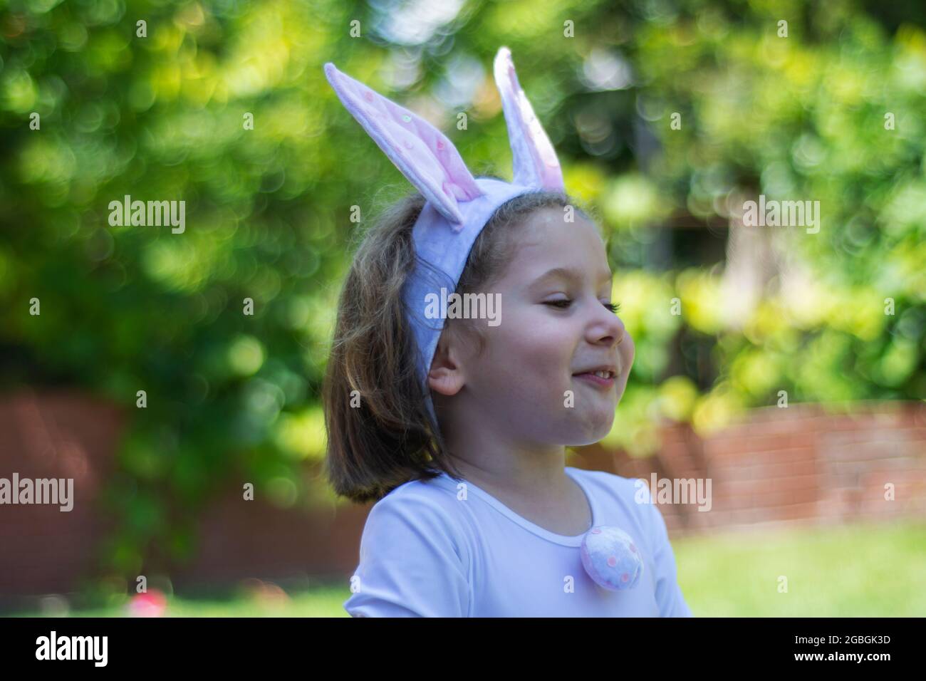 bambina in un costume coniglietto sta avendo un picnic nel giardino della sua casa. Foto Stock