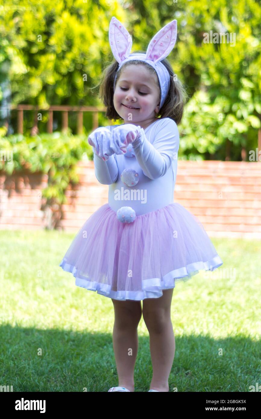 bambina in un costume coniglietto sta avendo un picnic nel giardino della sua casa. Foto Stock