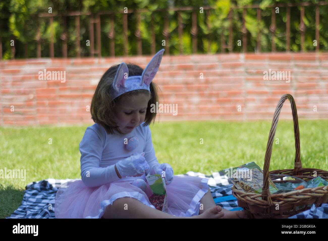 bambina in un costume coniglietto sta avendo un picnic nel giardino della sua casa. Foto Stock