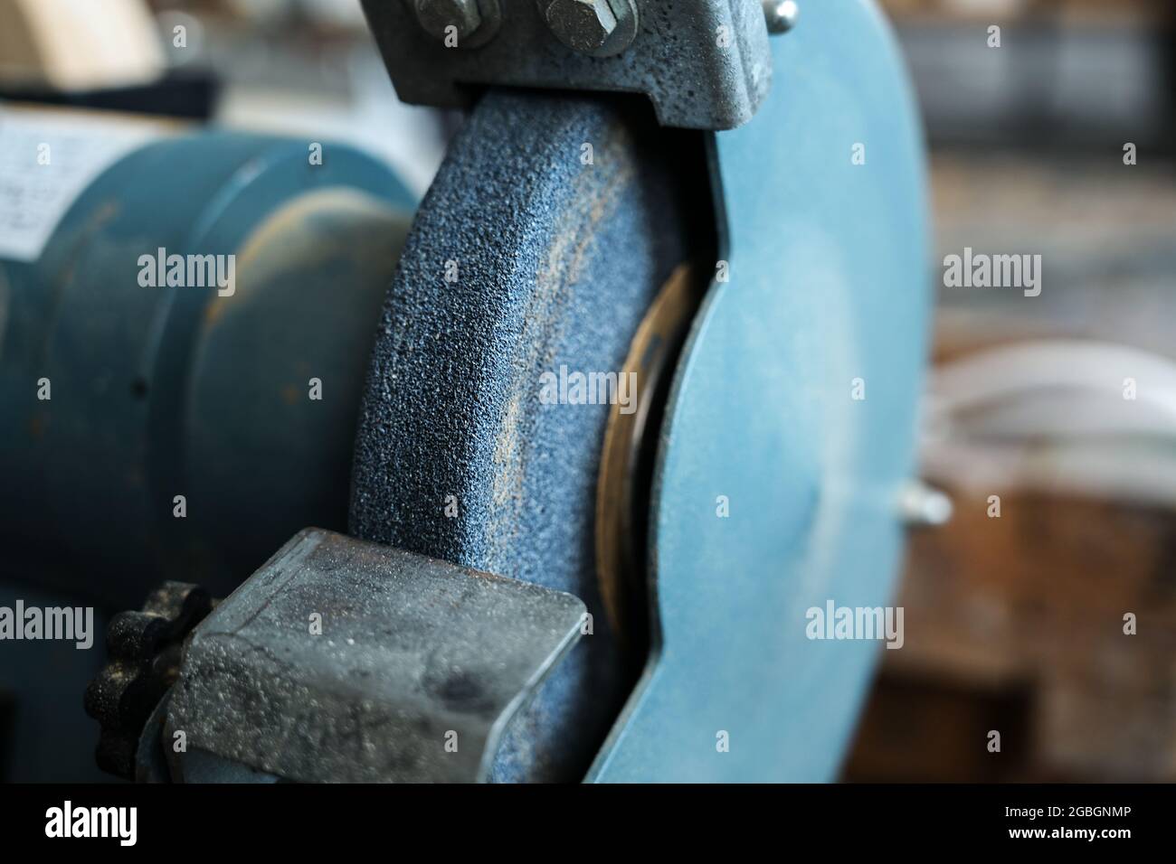 Particolare di una rettificatrice per affilare coltelli da carpenteria e levigare metalli nell'officina di un artigiano o di una artigiana, copia spazio, selezionato foc Foto Stock