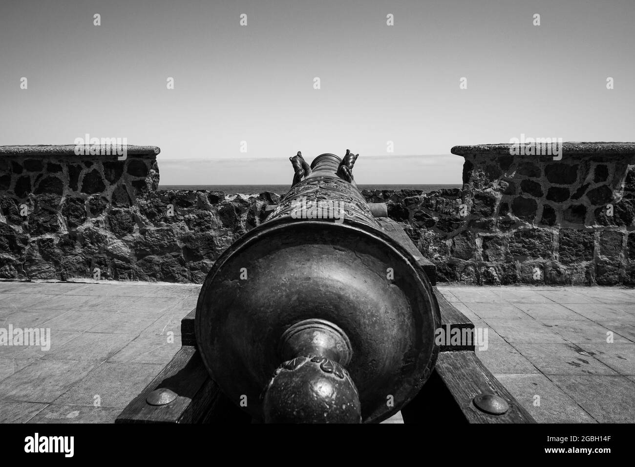 Scala di grigi di un vecchio cannone di fronte alla spiaggia Foto Stock Scala di grigi di un vecchio cannone di fronte alla spiaggia Foto Stock