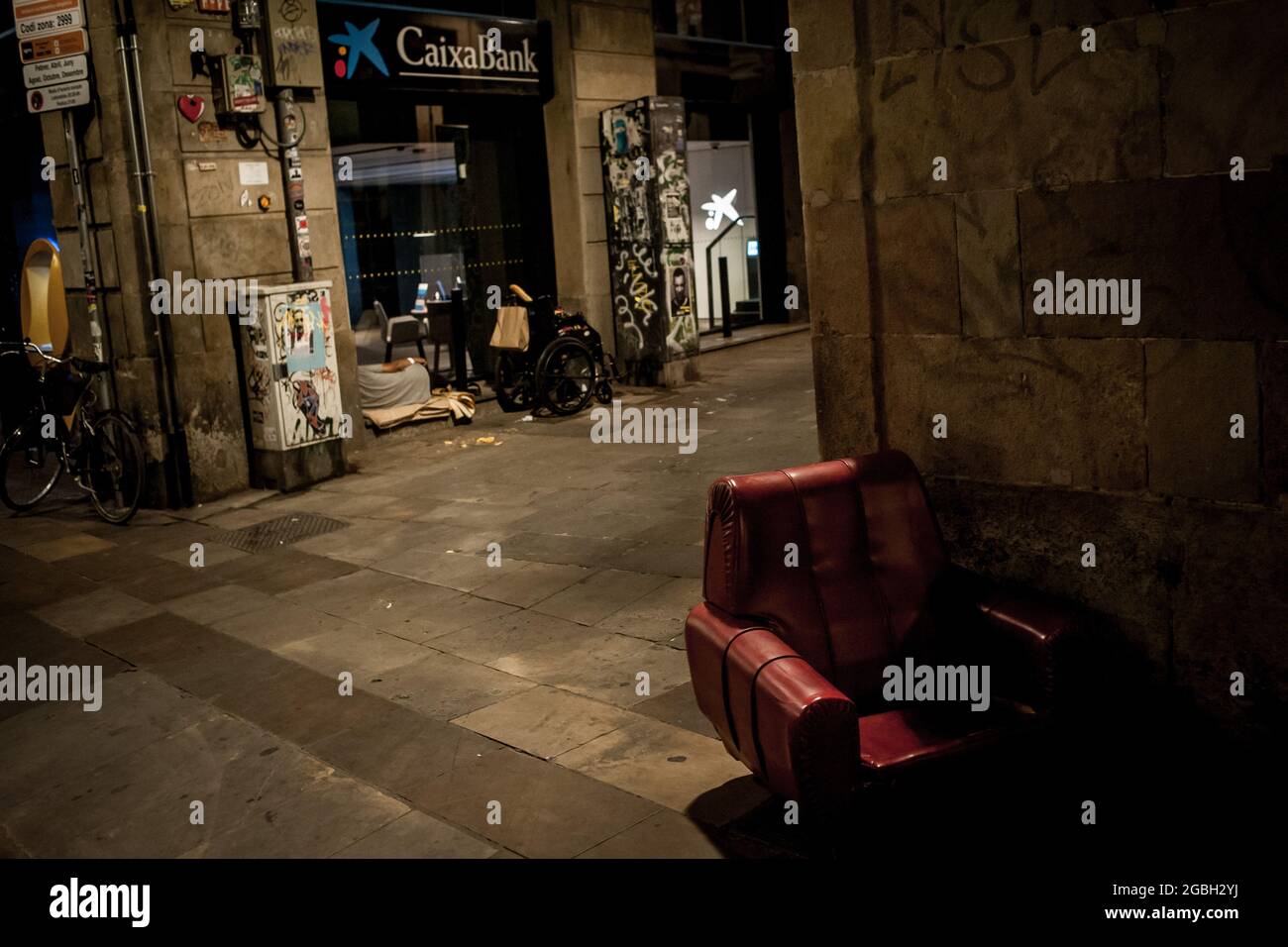 Un uomo dorme accanto a un ufficio bancario nella parte vecchia di Barcellona all'inizio del coprifuoco notturno. Foto Stock