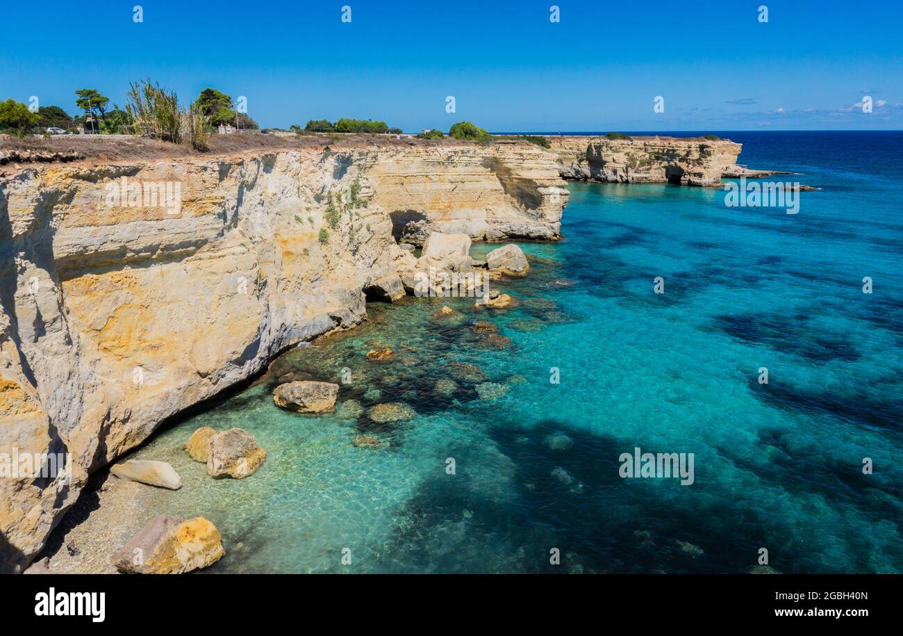 Torre Sant Andrea vicino Torre dell'Orso, Costa del Salento, Puglia, Italia. Bella spiaggia rocciosa con scogliere in Puglia. Acqua limpida saturata di turchese blu. Giornata estiva brillante. Nessuna gente. Foto Stock