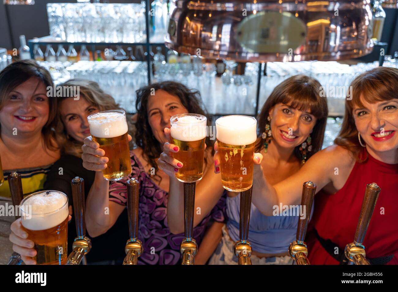 un gruppo di donne mature beve birra in un pub di fronte a una presa di birra Foto Stock