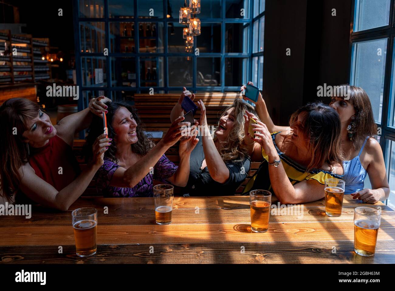 un gruppo di amici sorridenti prende un selfie con uno smartphone mentre beve birra in un pub Foto Stock