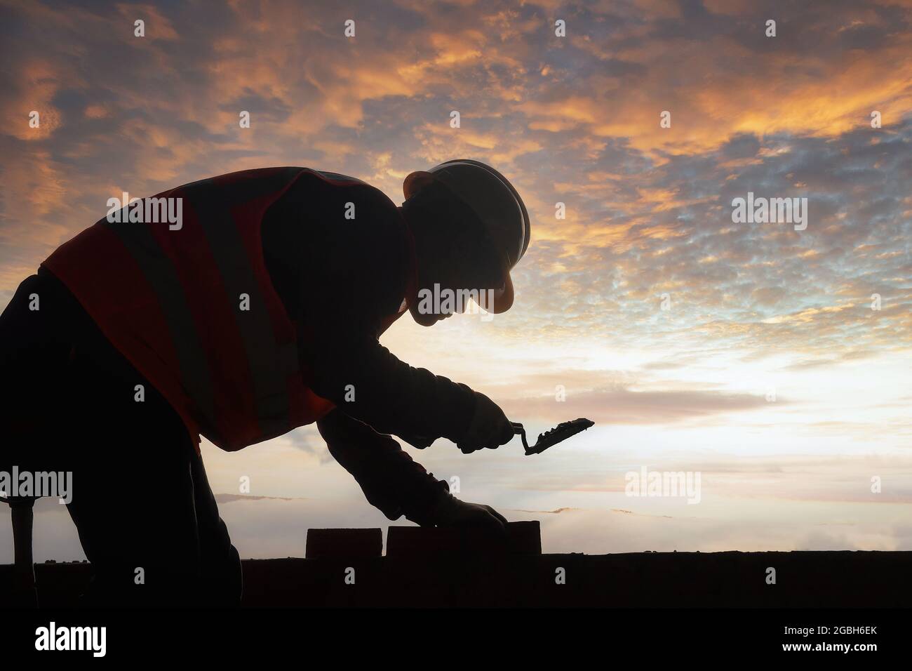 Silhouette di un muratore che costruisce un muro su un cantiere, in Thailandia Foto Stock