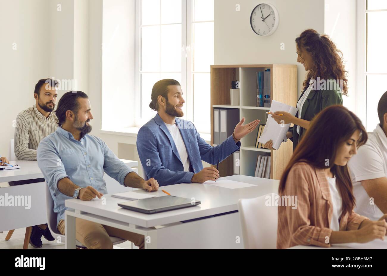 Insegnante o allenatore che ha corso di formazione con un gruppo di persone felici in classe moderna Foto Stock