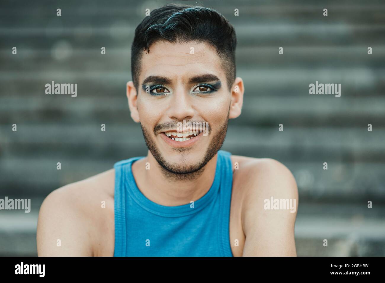 Giovane gay sorridente sulla macchina fotografica all'aperto in città - Focus on Face. Foto Stock