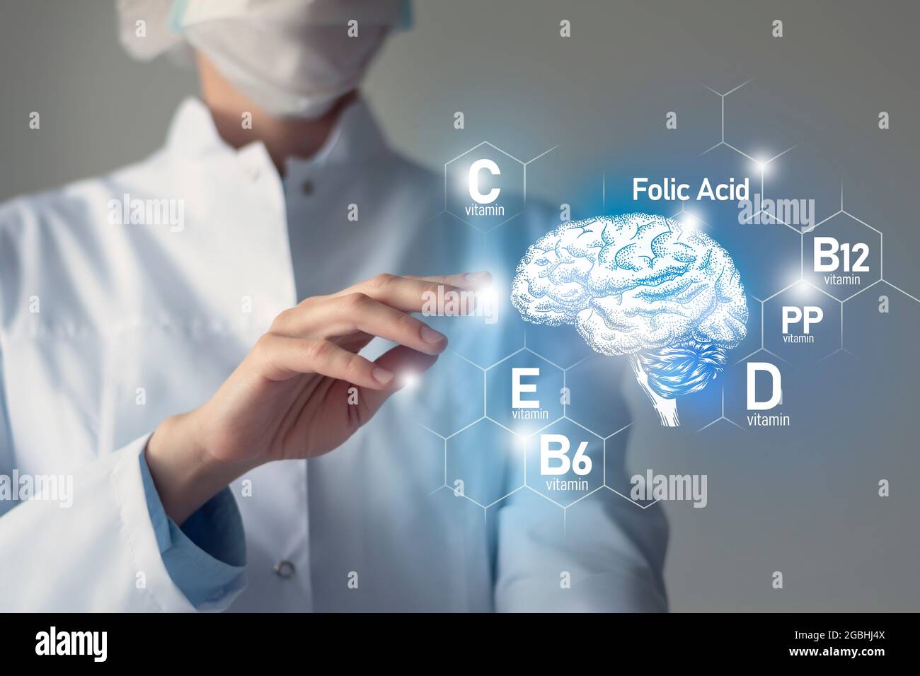 Sostanze nutritive essenziali per la salute del cervello, tra cui vitamina C, vitamina B, acido folico, vitamina PP. Ritratto offuscato del medico che tiene evidenziato cervello. Foto Stock