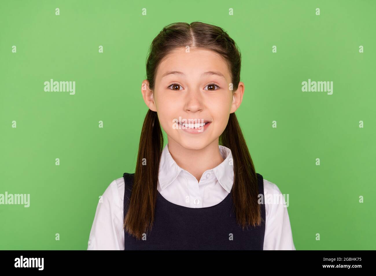 Foto di affascinante dolce scuola ragazza vestiti abiti formali sorridente isolato sfondo di colore verde Foto Stock