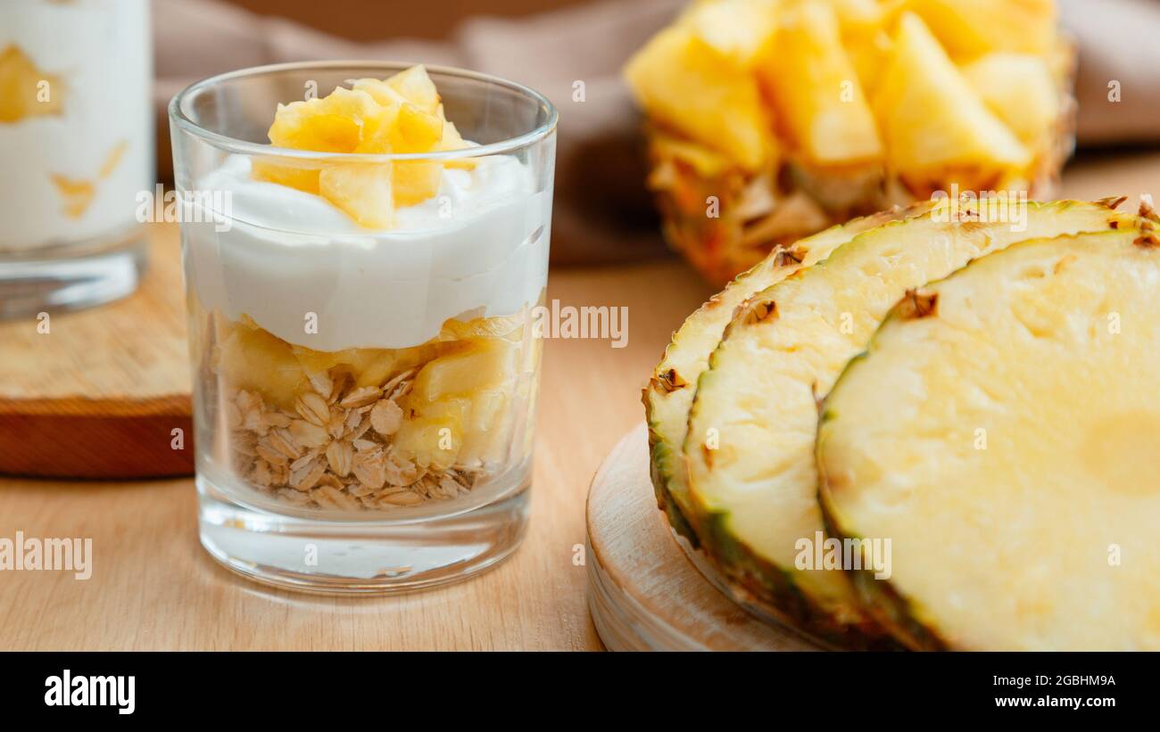 Delizioso dessert all'ananas. Prima colazione dessert con granola di avena, yogurt greco e ananas a strati in vetro con ingredienti tritati freschi succosi Foto Stock