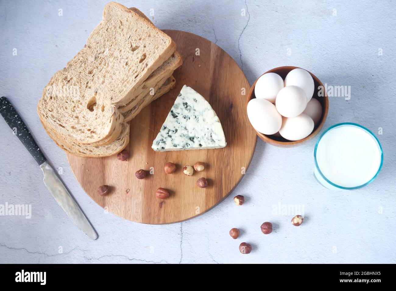 formaggio blu, latte, pane marrone, uova e mandorle noci sul tavolo. Foto Stock