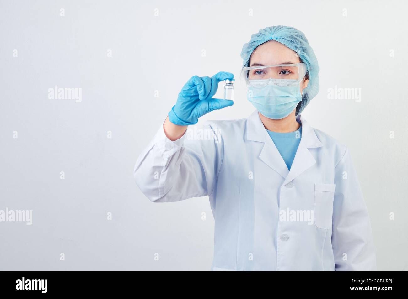 Medico o scienziato professionista che tiene in mano il flaconcino di vaccino Covid-19 in laboratorio per il trattamento con guanti da maschera e camice da laboratorio su sfondo bianco Foto Stock