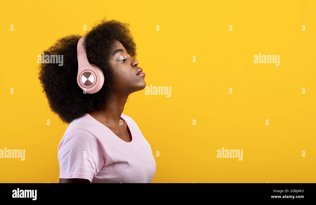 Meditazione, relax e riposo con la musica. Calma donna afroamericana in cuffie wireless con occhi chiusi Foto Stock