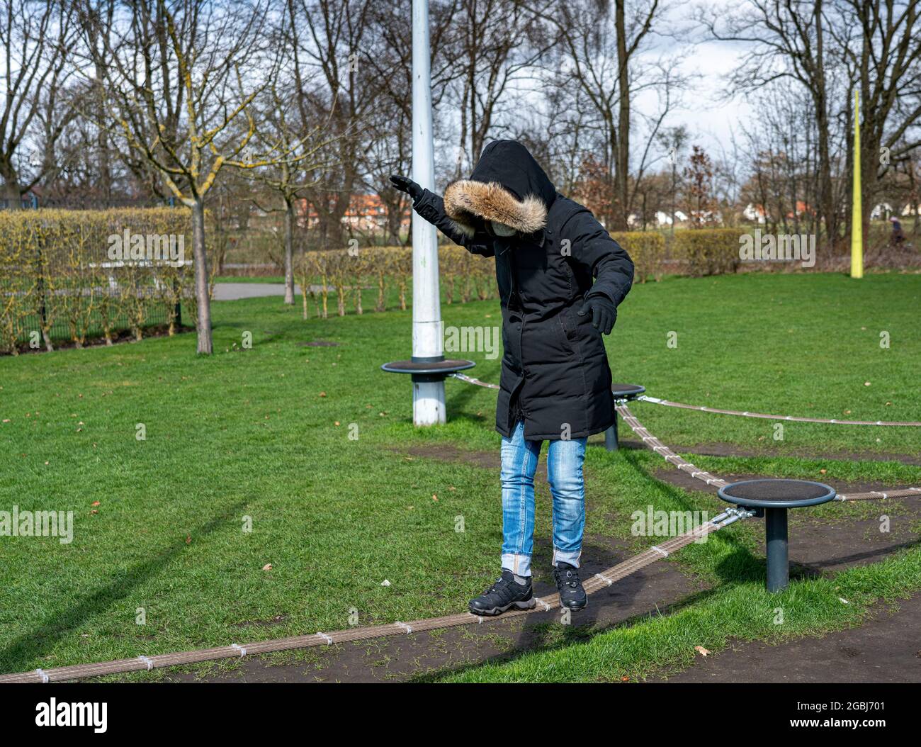 Donna con giacca invernale Balancing su attrezzature sportive nel Parco Foto Stock