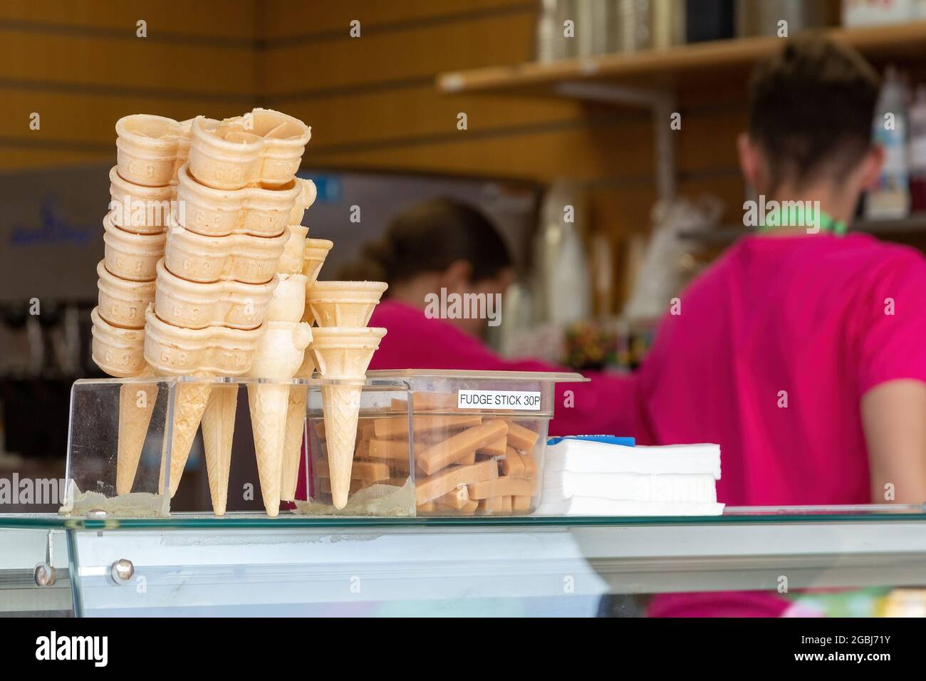Coni gelato in un negozio di gelaterie con lavoratori in background Foto Stock