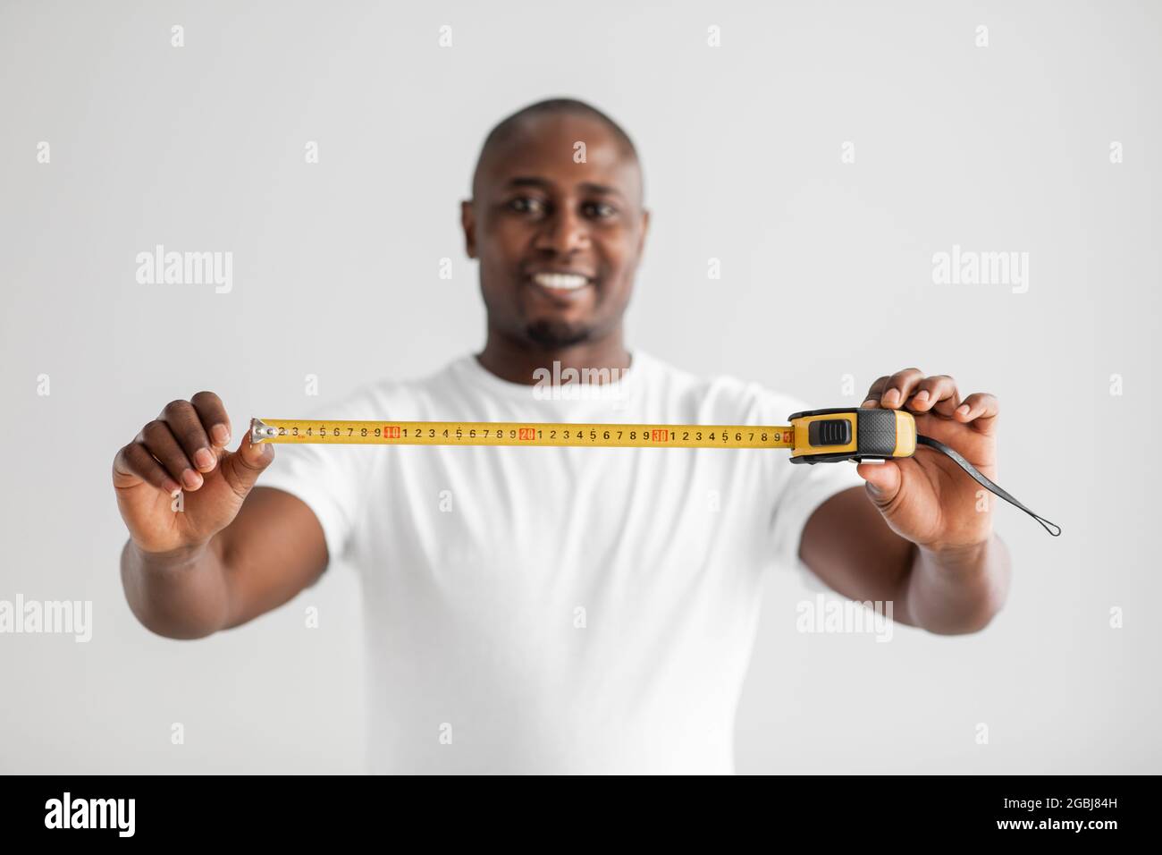 Uomo di costruzione, riparazione e ristrutturazione della casa. Eccitata afroamericana handyman che tiene la misura del nastro-linea Foto Stock