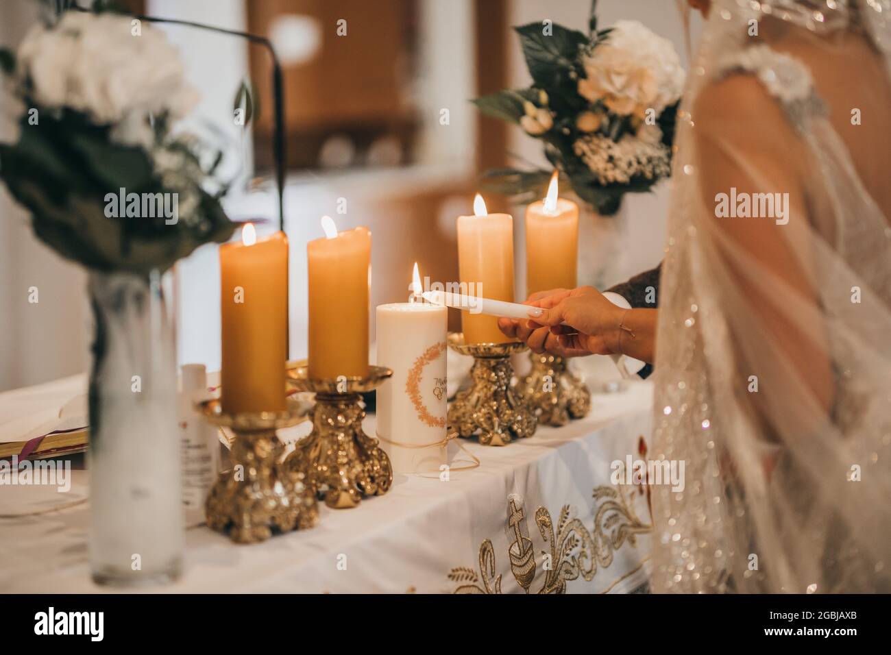 Primo piano delle mani della sposa e dello sposo che bruciano le candele Foto Stock