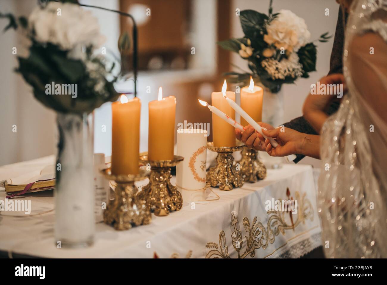 Primo piano delle mani della sposa e dello sposo che bruciano le candele Foto Stock