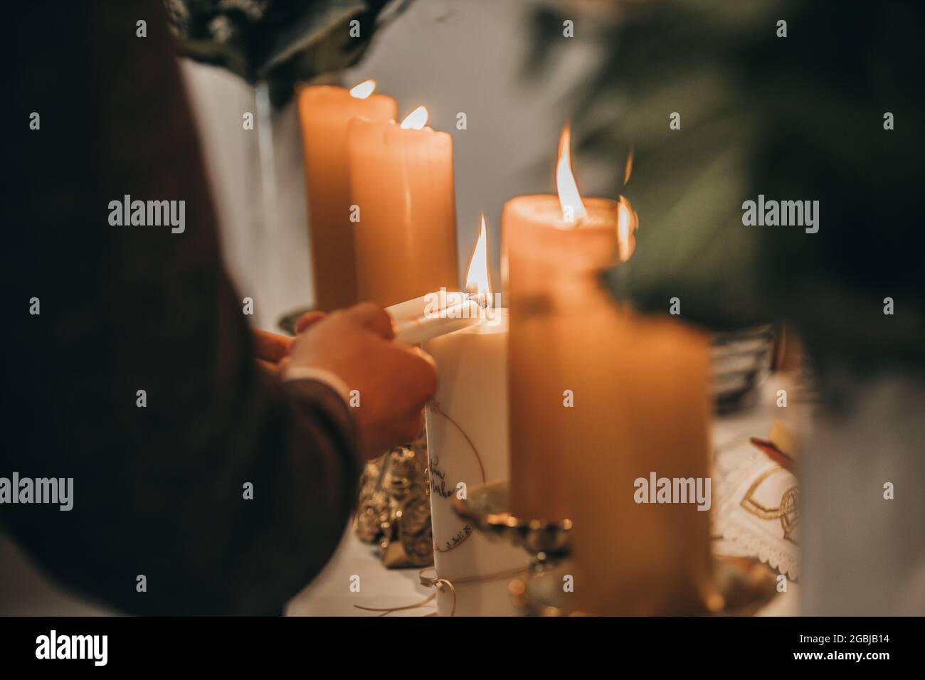 Primo piano di una coppia di mani che bruciano le candele Foto Stock