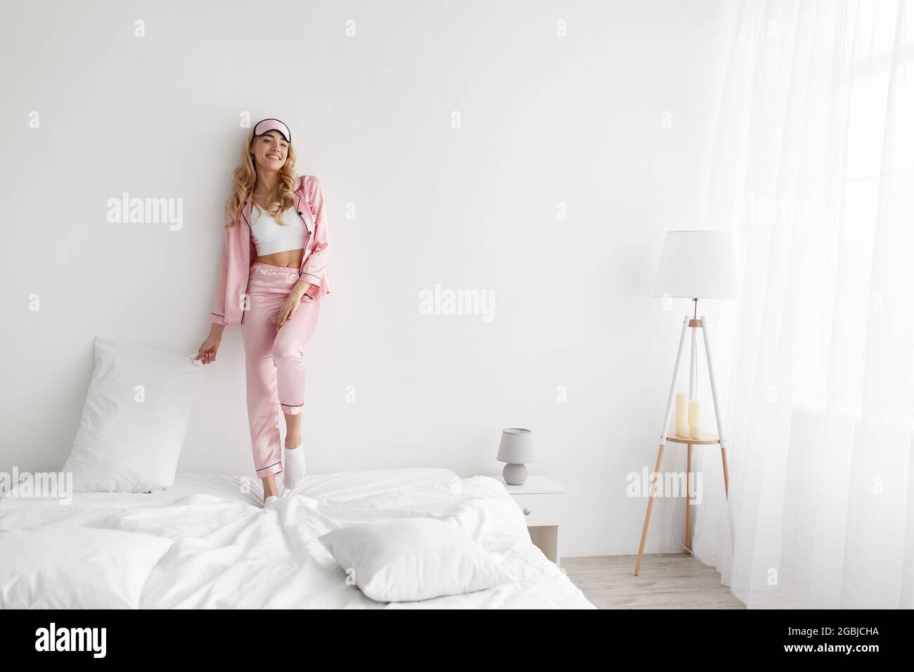 Felice giovane donna godendo di sole mattina a letto dopo un sonno sano Foto Stock
