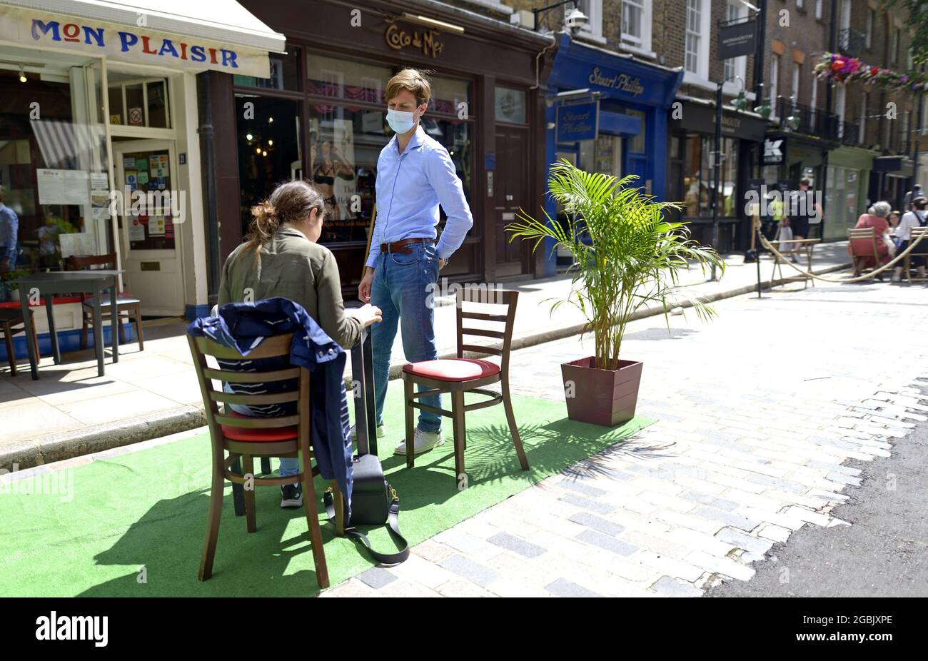 Londra, Inghilterra, Regno Unito. Uomo che serve una donna sola ad un tavolo esterno durante la pandemia di COVID, Mon Plaisir, Covent Garden, luglio 2021 Foto Stock