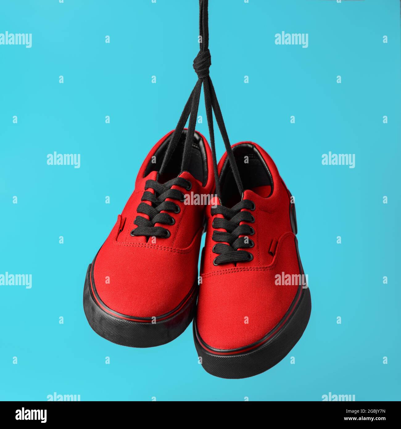 Paio di nuove gengivali rosse appese su lacci su sfondo blu. Concetto di moda urbana. Primo piano Foto Stock