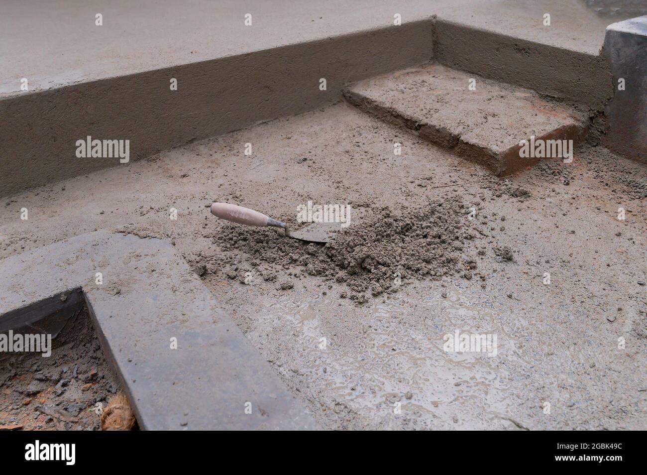 I terreni ad altezze diverse vengono intonacati utilizzando manualmente cazzuola e cemento, immagine stock. Foto Stock