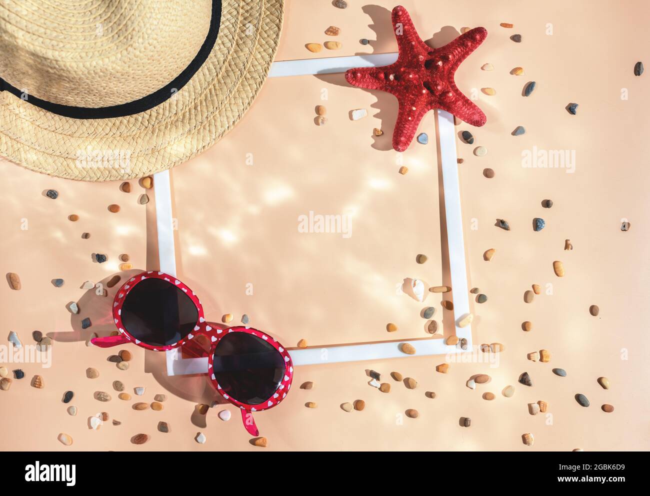 Appartamento estivo posato. cappello, stella marina, occhiali da sole, conchiglia e cornice quadrata bianca su sfondo Set Sail Champagne. Concept mare, vacanza. Vista dall'alto, con copia Foto Stock