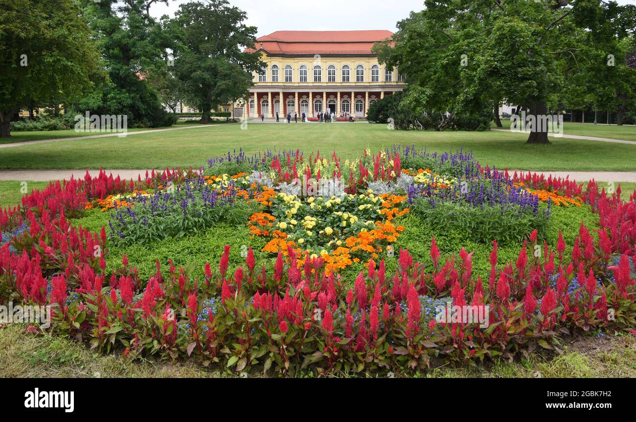 16 luglio 2021, Sassonia-Anhalt, Merseburg: Fiori fioriscono nel parco di fronte al salone Schlossgarten. L'edificio a due piani, costruito tra il 1731 e il 1735 secondo i progetti di Johann Michael Hoppenhaupt in stile barocco e commissionato dal duca Moritz Wilhelm di Sassonia-Merseburg, era destinato a servire come sala banchetti per feste in giardino. Il piano terra ha una sala con colonne toscane sul lato sud, che originariamente si apriva sul giardino attraverso porte francesi. Attualmente, il piano terra è utilizzato da un artista come studio aperto. Foto: Waltraud Grubitzsch/dpa-zentralbild/ZB Foto Stock