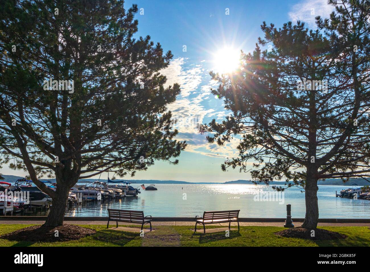 Panchine pubbliche che si affacciano su un lago soleggiato Foto Stock