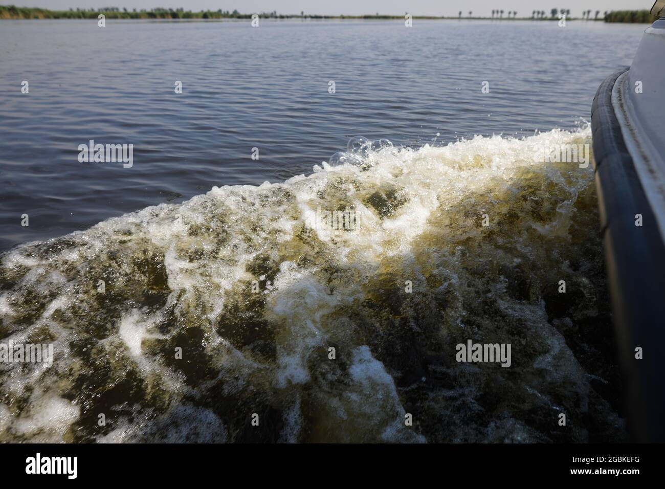 Dettagli con il surf creato da una piccola barca in movimento su un lago. Foto Stock
