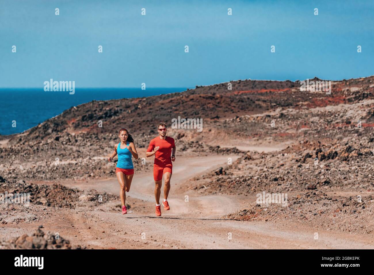 I corridori corrono velocemente nel paesaggio desertico . Coppia di atleti di allenamento sportivo estivo all'aperto. L'uomo e la donna si allenano insieme Foto Stock