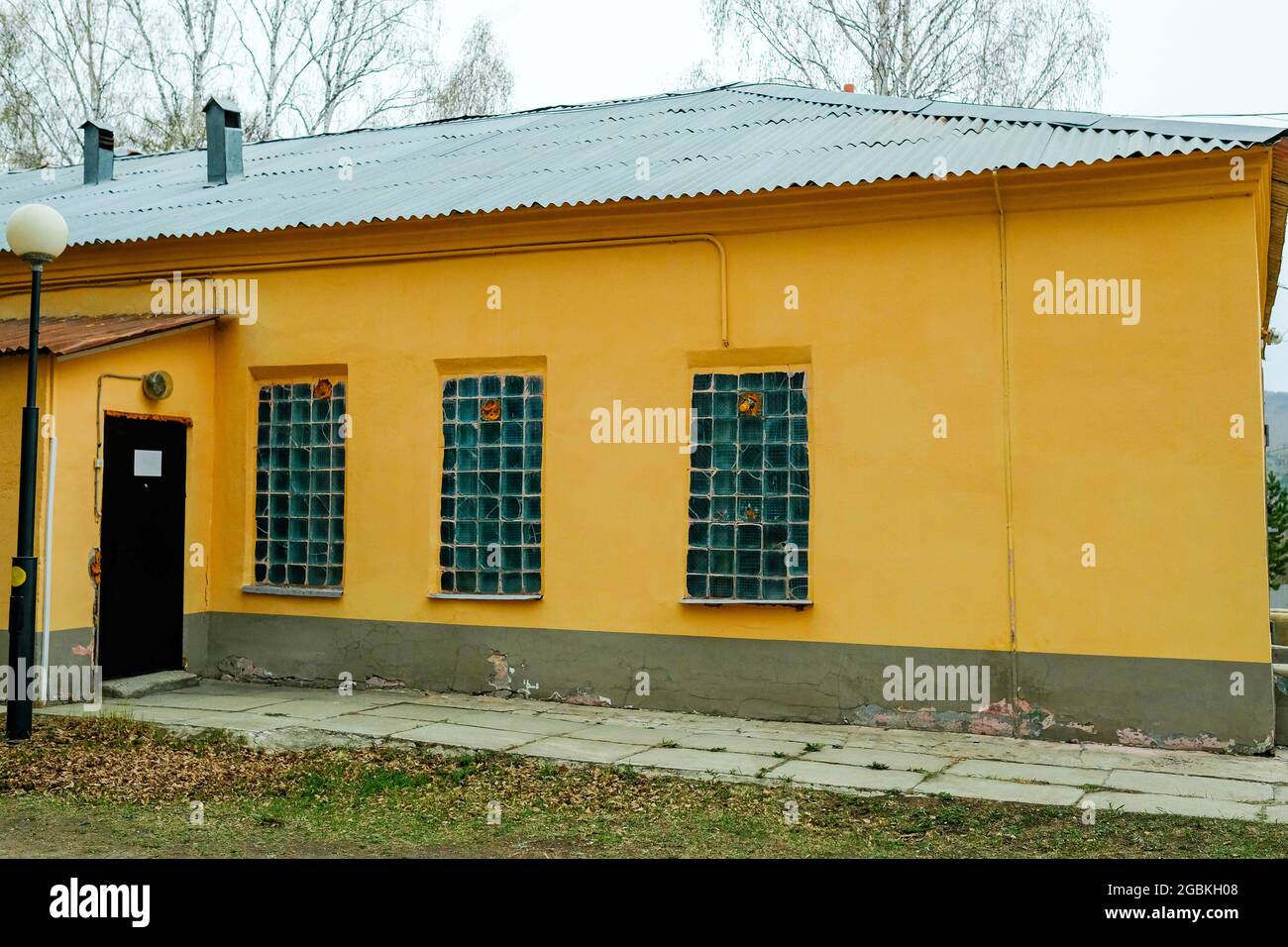 Vecchia casa di costruzione sovietica gialla. Piccole finestre opache. Nessuno. Foto Stock