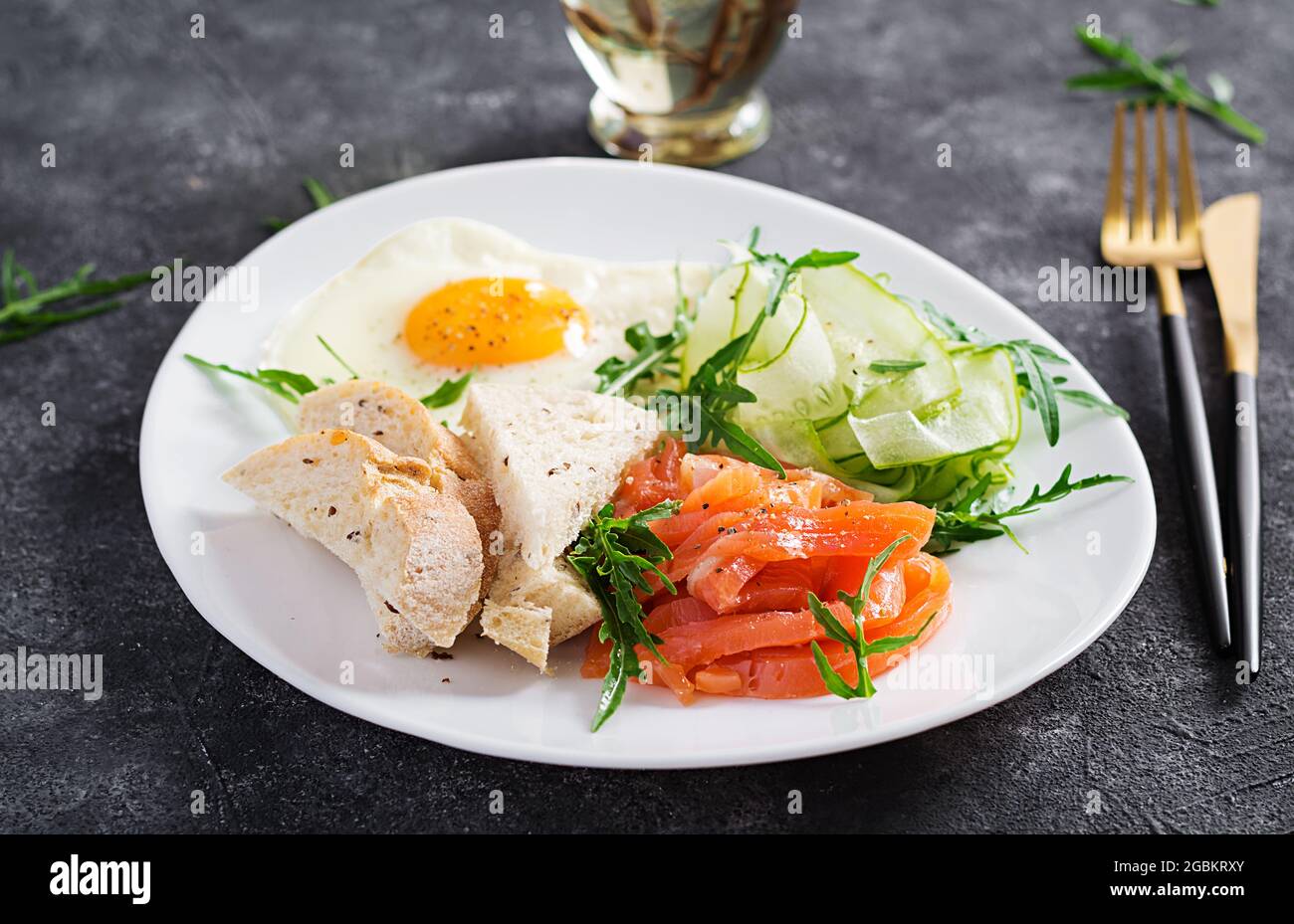 Prima colazione dietetica. Insalata di salmoni con verdure, cetrioli, uova fritte e pane. Foto Stock