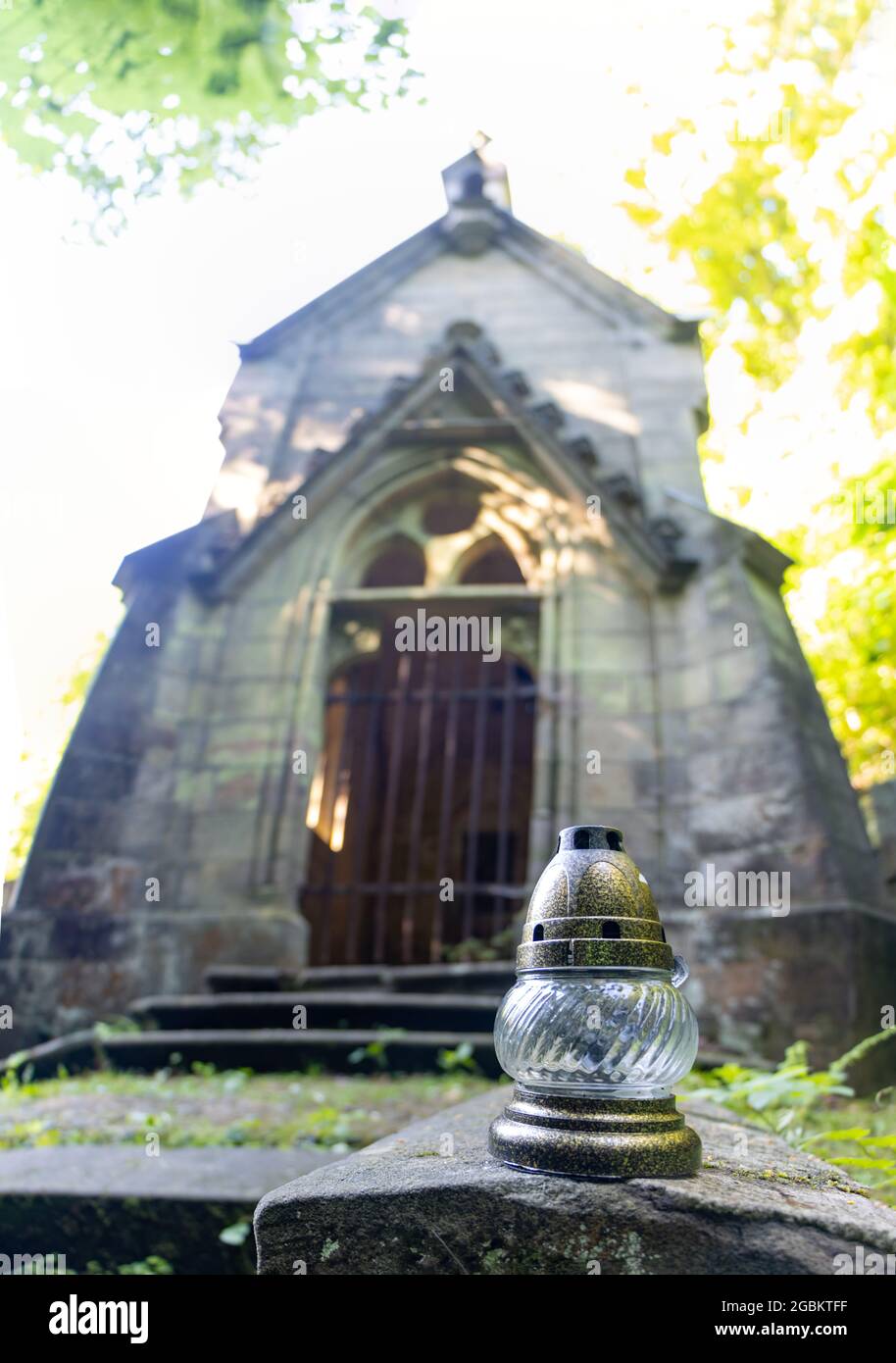 Una piccola lampada di fronte alla cappella pseudo-gotica con una tomba nel vecchio cimitero. Foto Stock