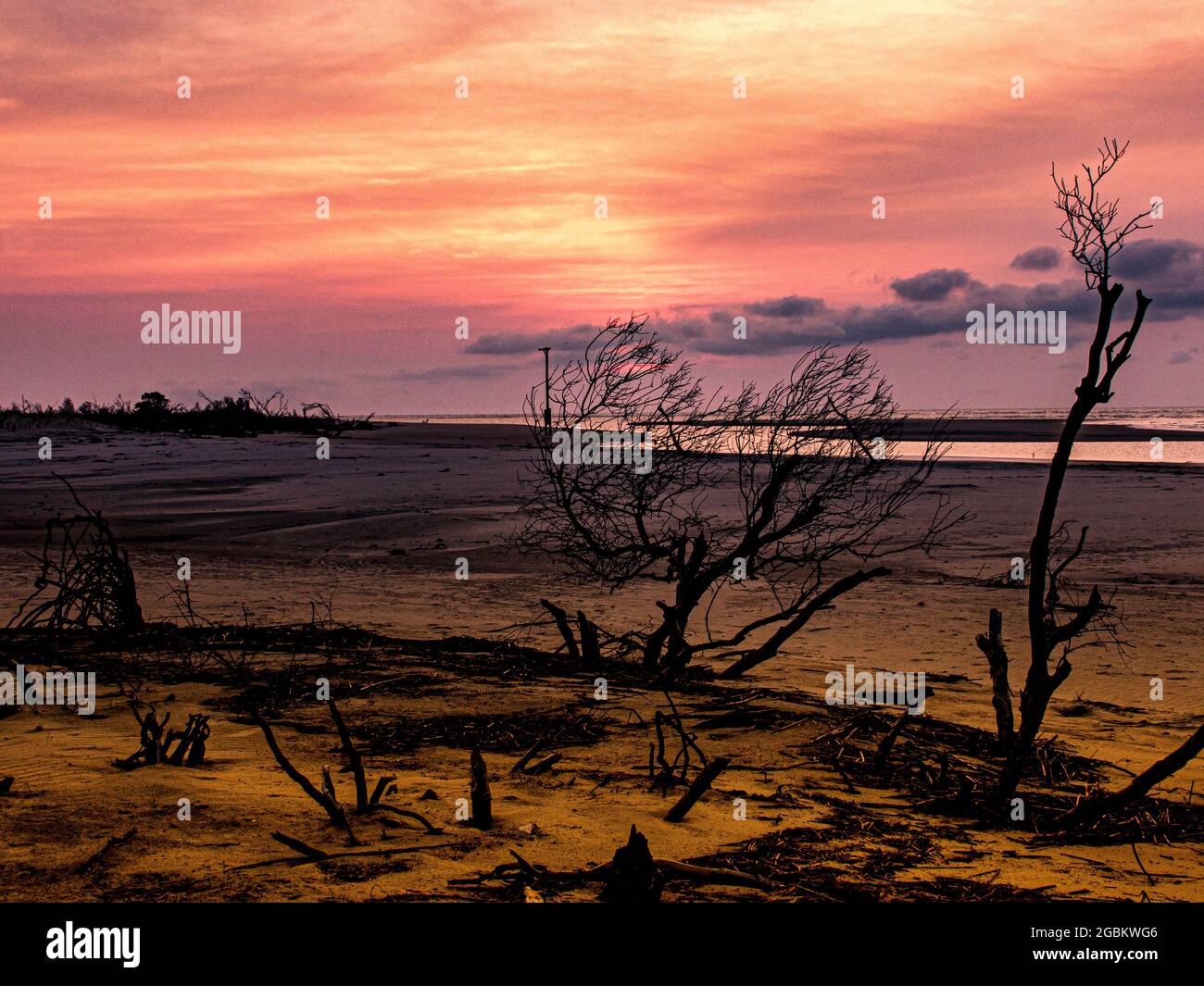 Mare di cieli rossi dorati mentre il sole del mattino sorge su un'isola panoramica barriera. Foto Stock