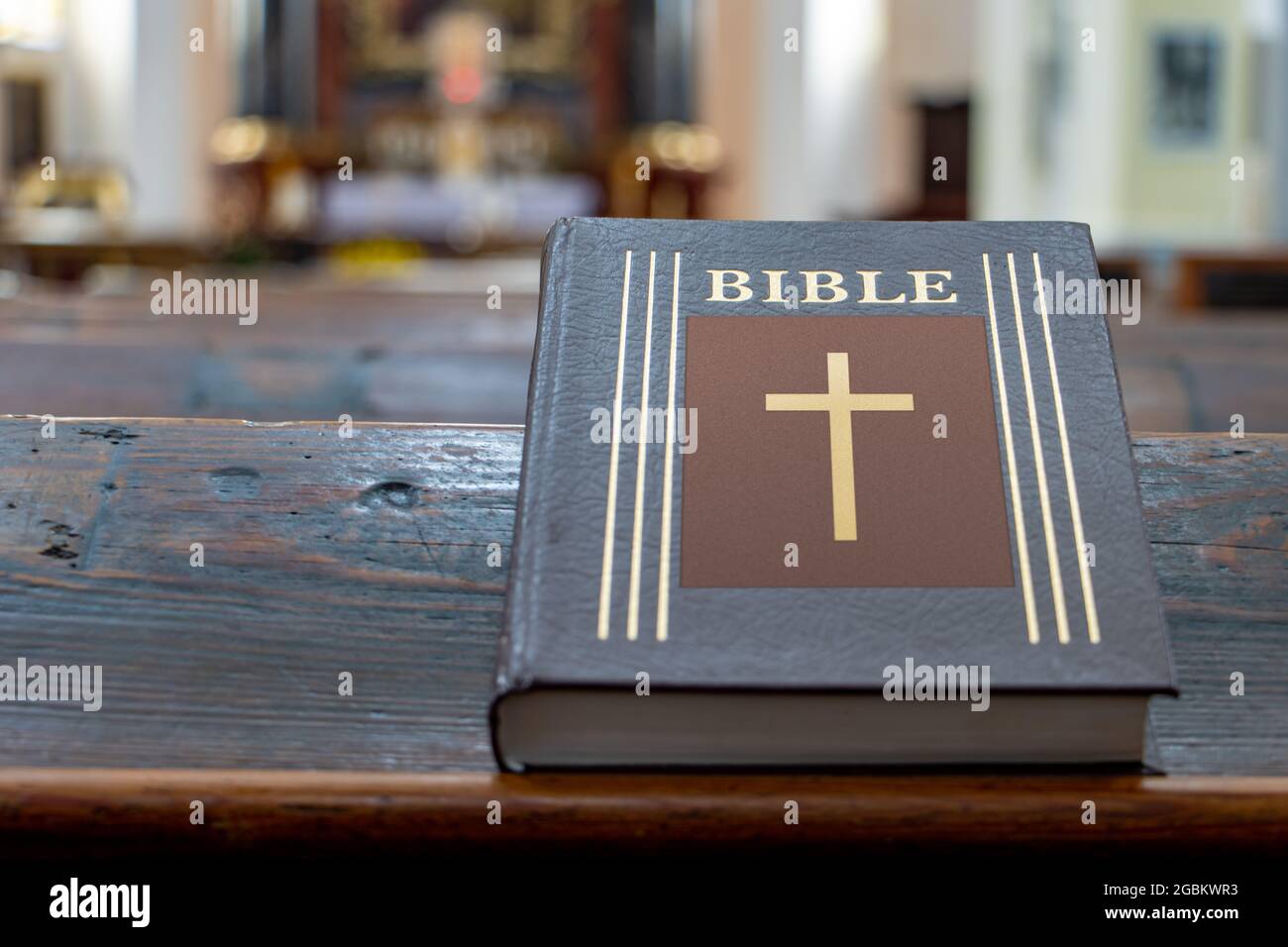 La Bibbia sulla tavola di una panchina di preghiera nella chiesa con un altare. Foto Stock